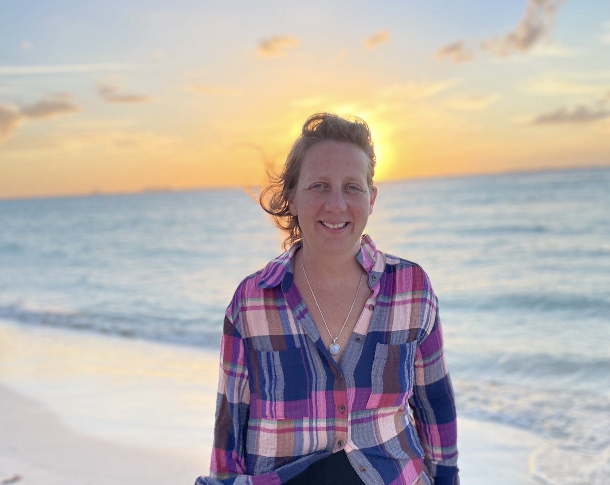 Ashley Millikin smiling by the ocean at sunset